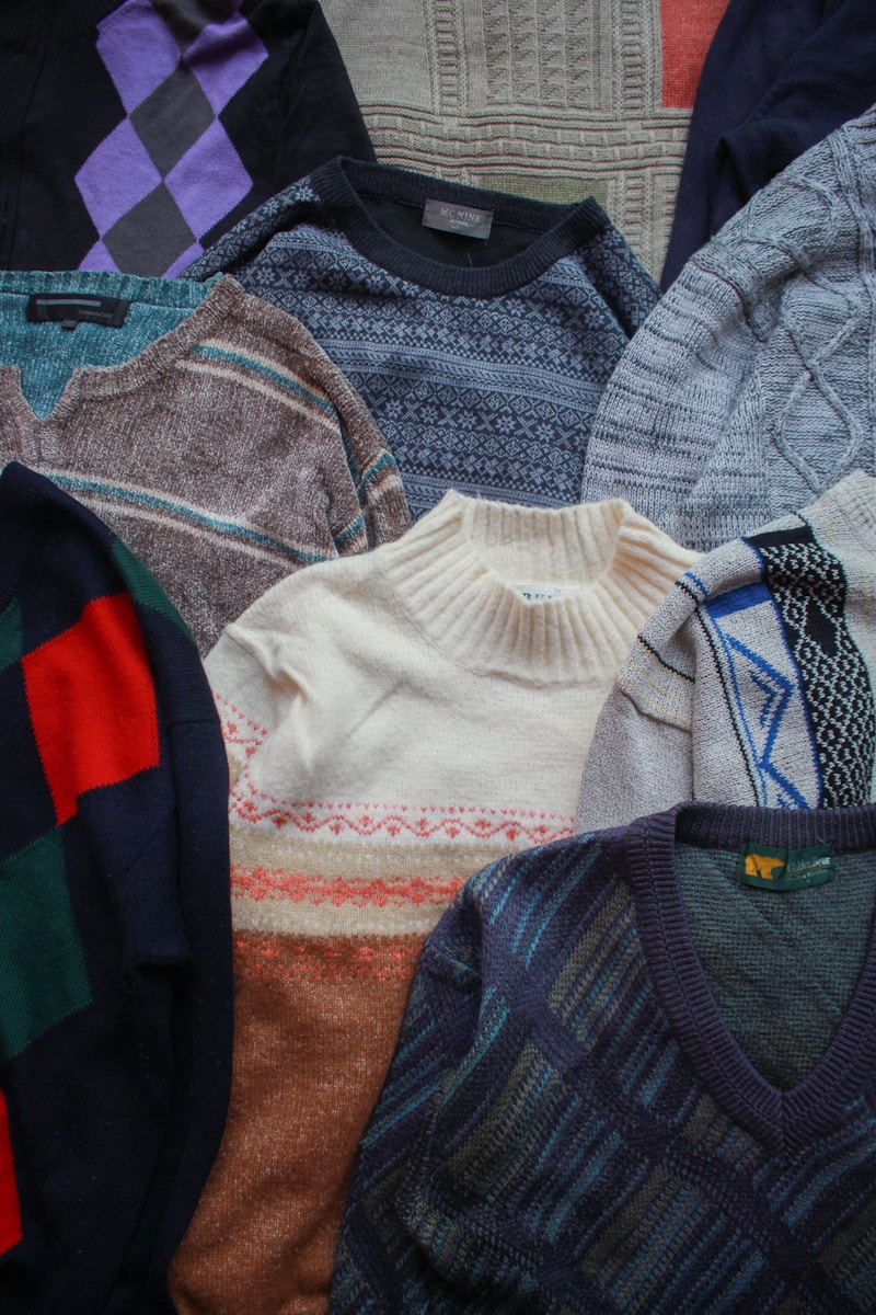 a pile of sweaters sitting on top of a bed